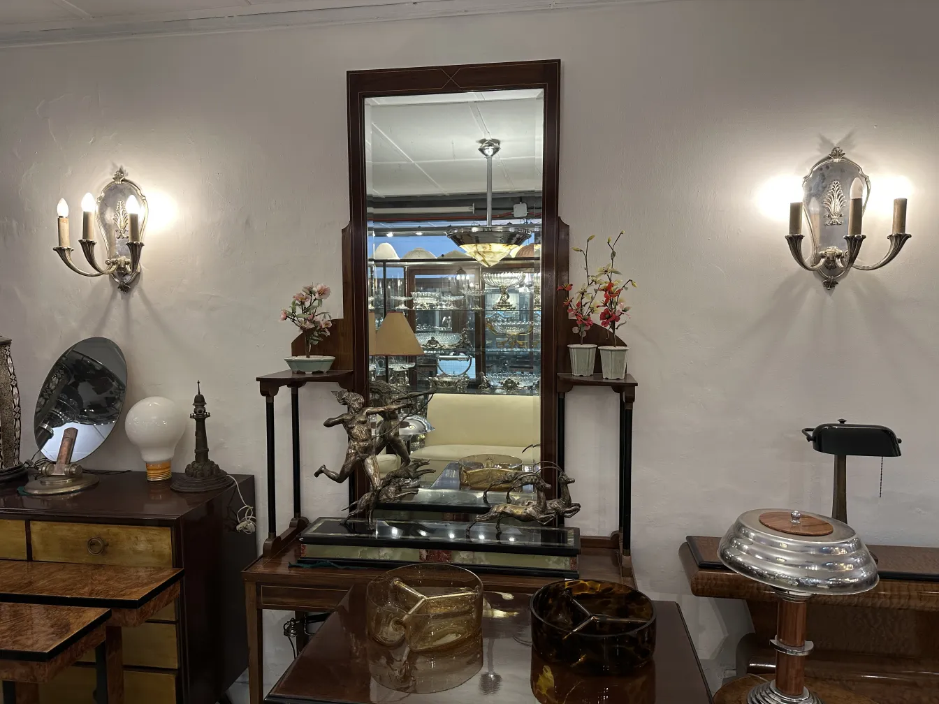 Antique pair of sconces beside a large mirror in an elegant setting.