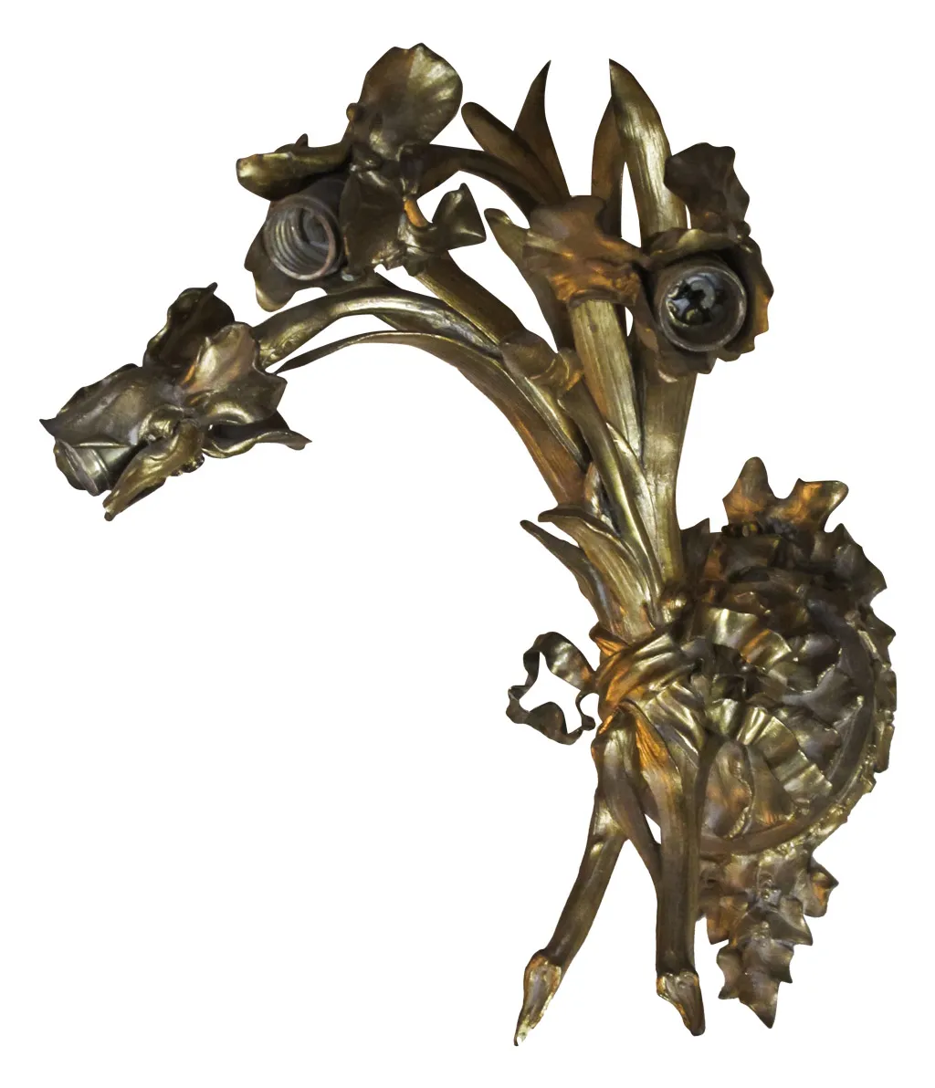Antique bronze sconces shaped like flowers on the wall.