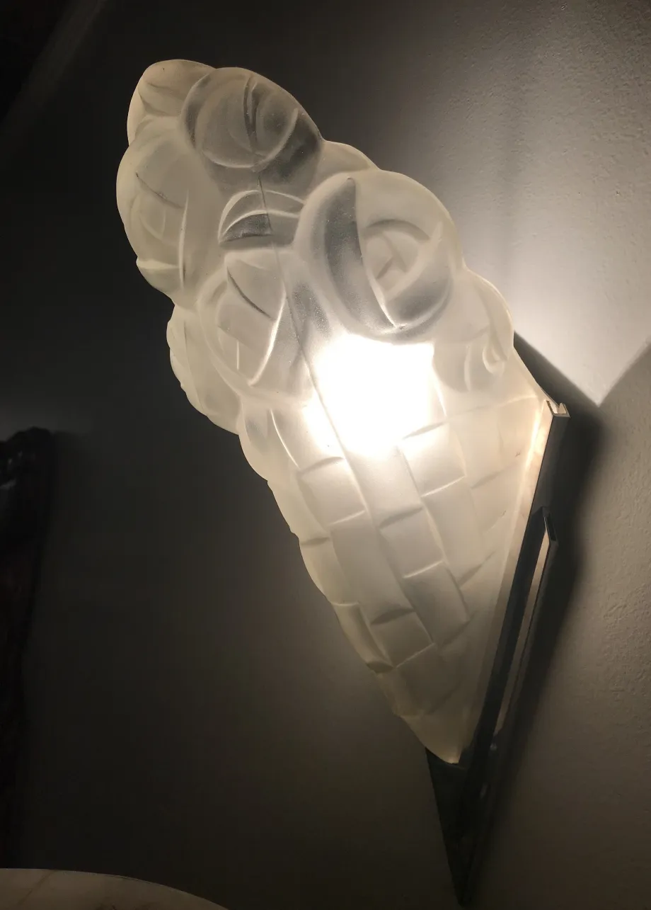 Antique wall sconce with intricate shape and soft light, set in a dim room