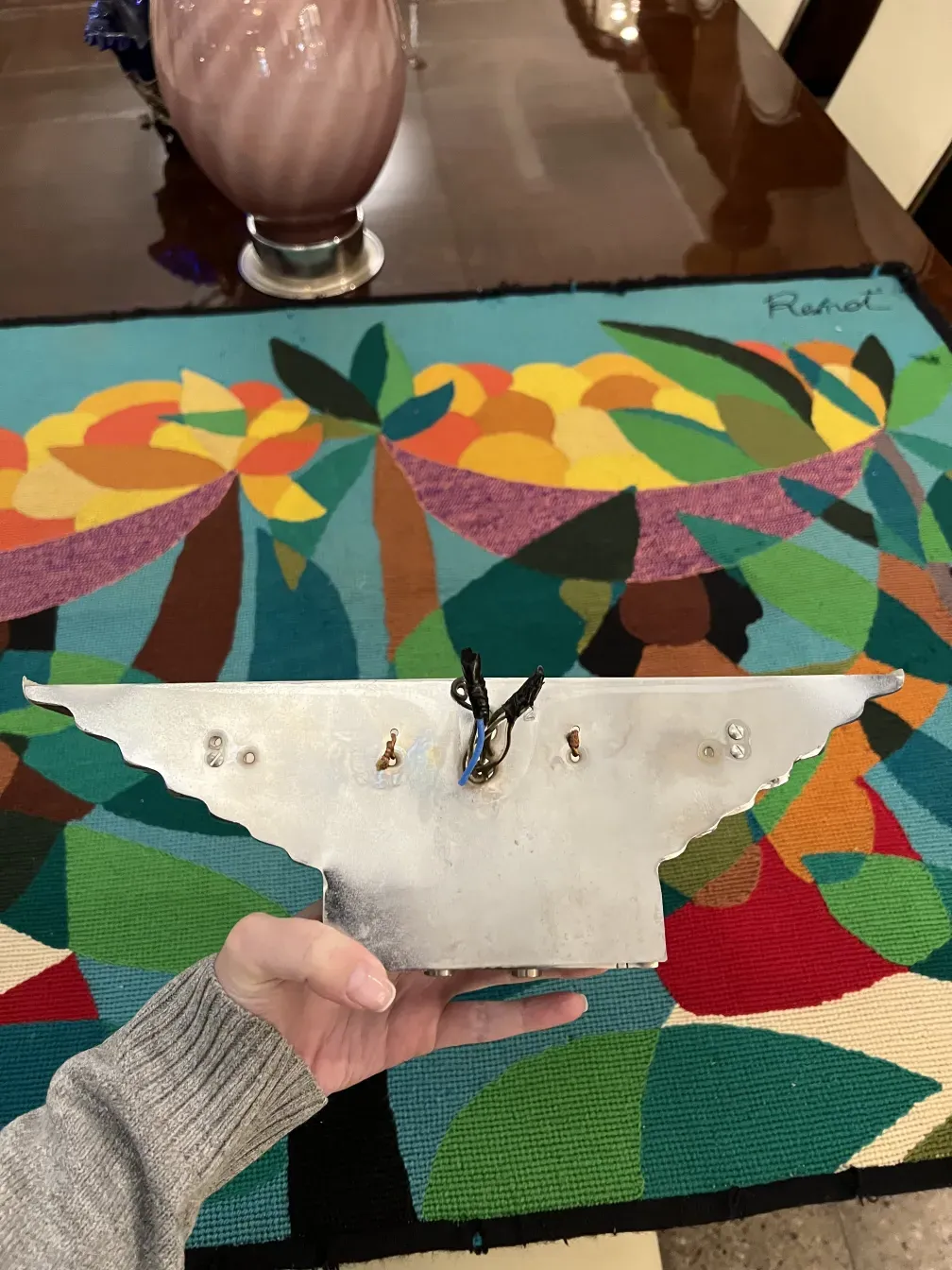 An antique pair of sconces with a unique design on a colorful table.
