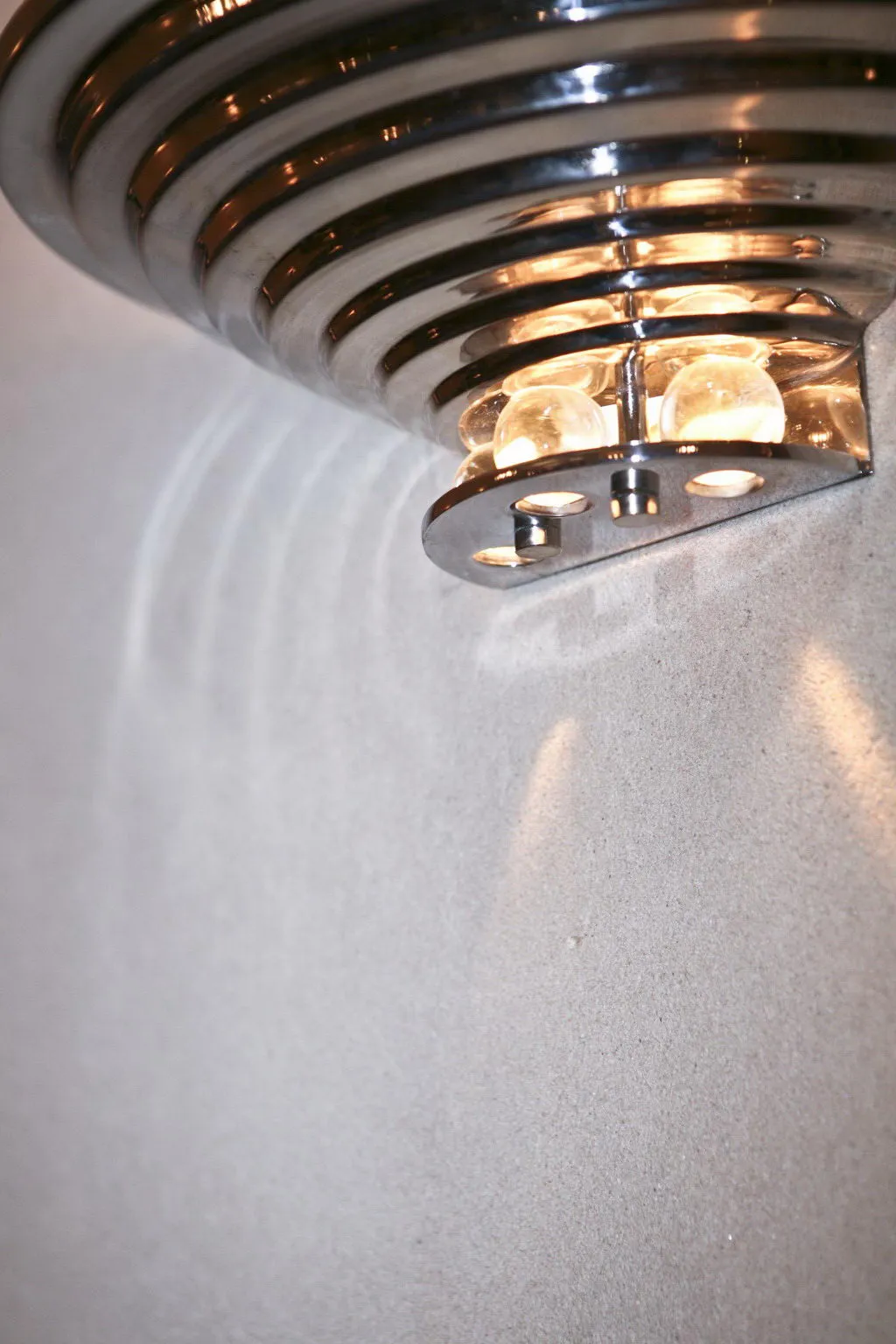 Pair of antique sconces with warm light on smooth wall.