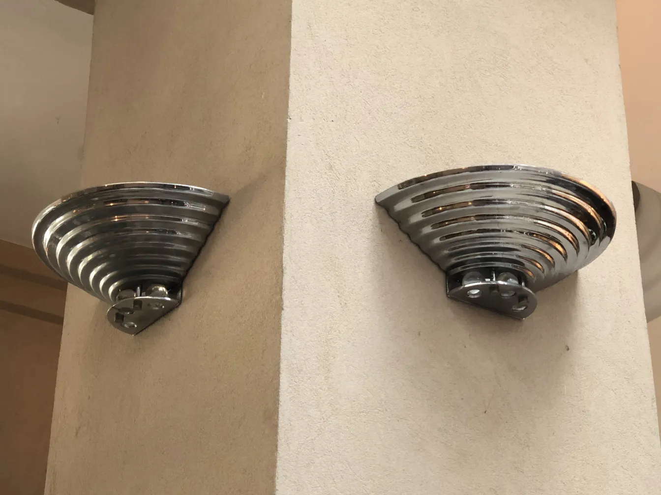 Pair of antique sconces with curved design, mounted on a light wall.