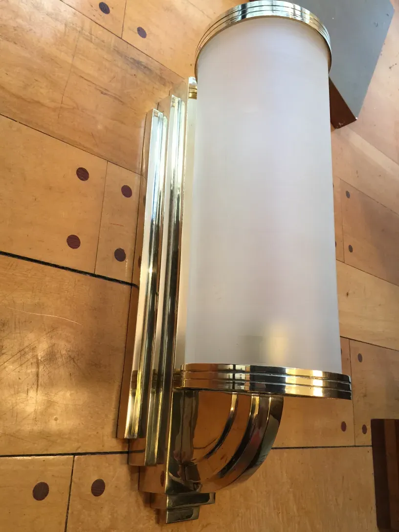 Antique pair of sconces with a gold finish and frosted glass in a classic setting.