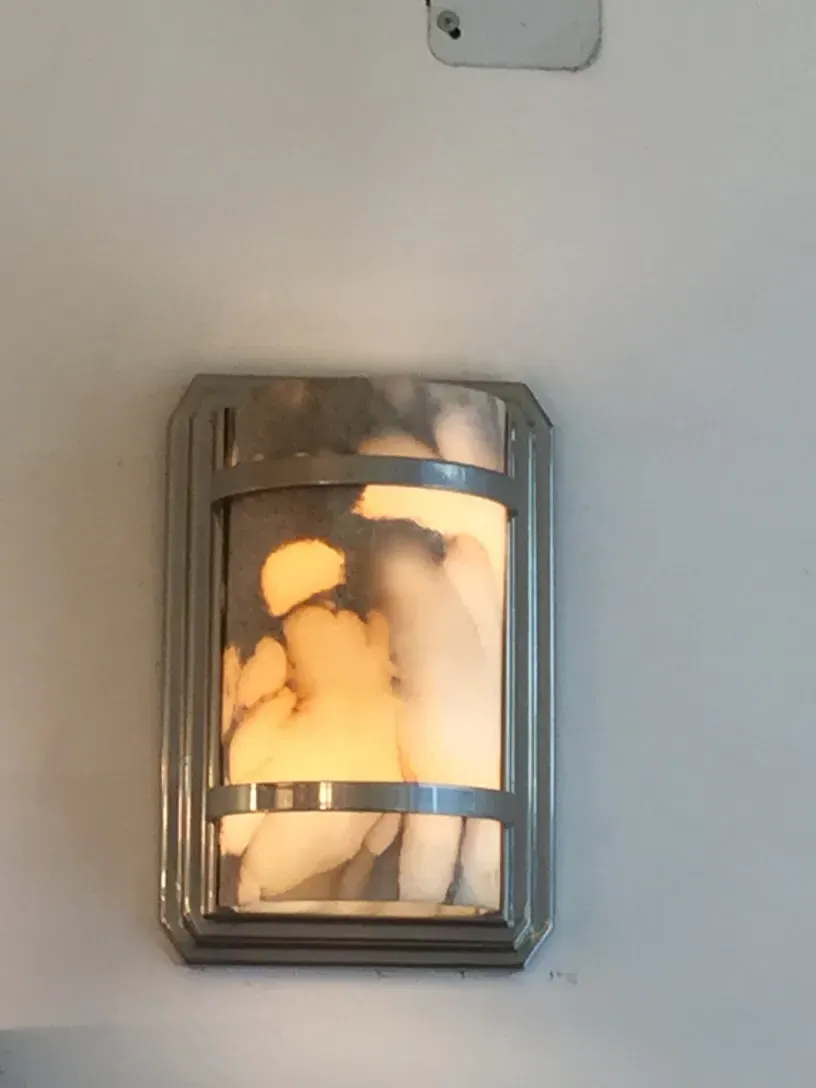 Pair of antique sconces with warm light on white wall.