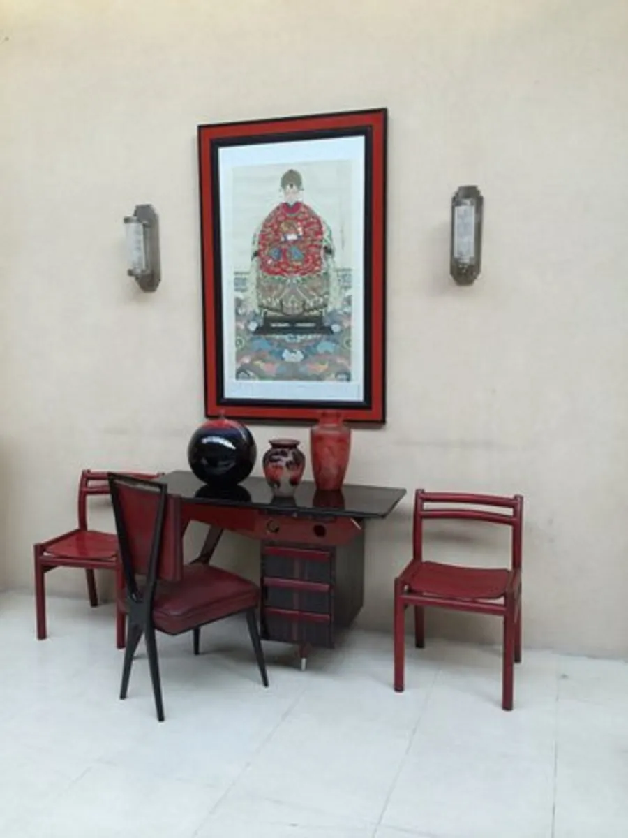 A pair of antique sconces in an elegant setting with red chairs and a colorful painting.