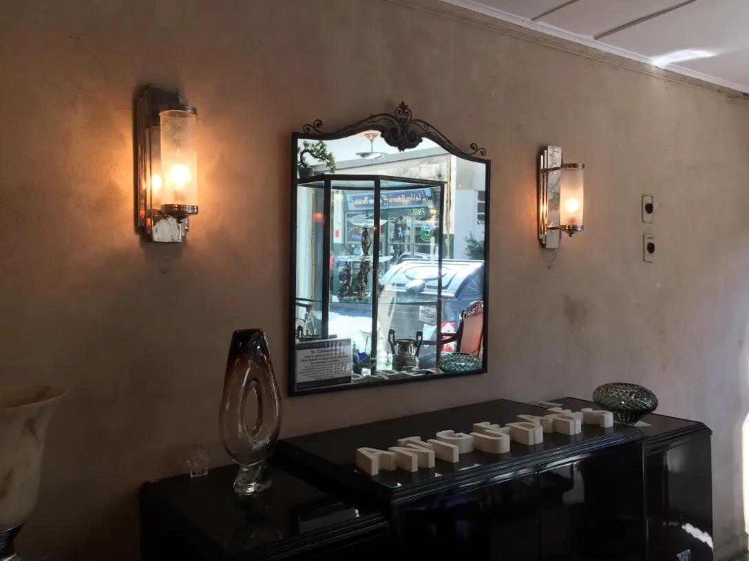 Antique pair of sconces lighting a room with a mirror