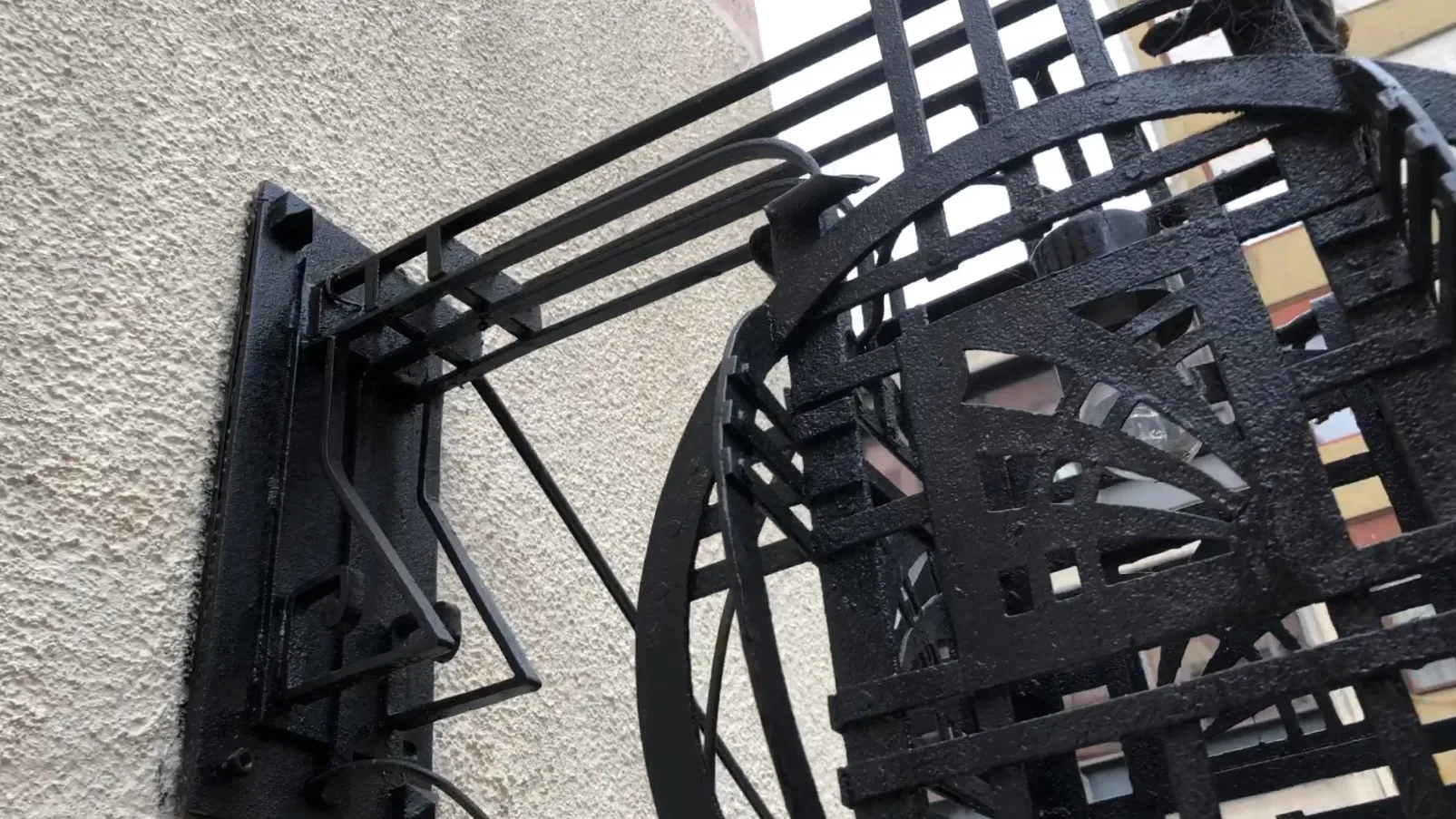 Antique sconces with artistic design, black color, mounted on textured wall.