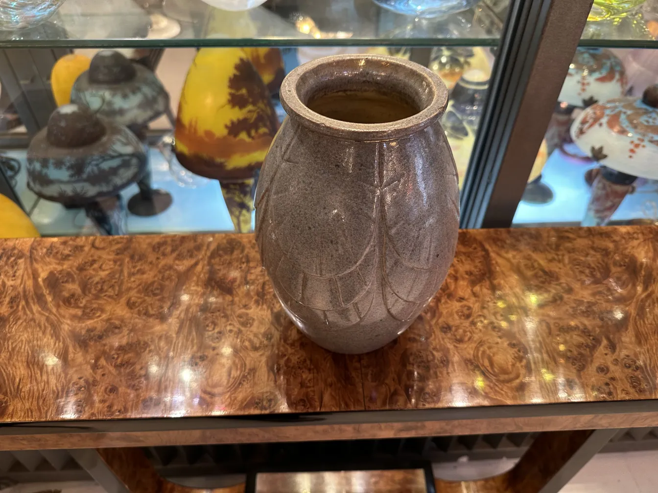 Antique ceramic vase with subtle decoration, background with assorted items.