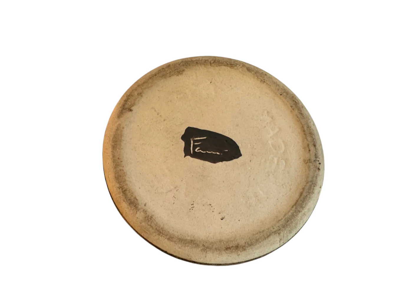 Top view of an antique ceramic cup with a mark. Light beige color.