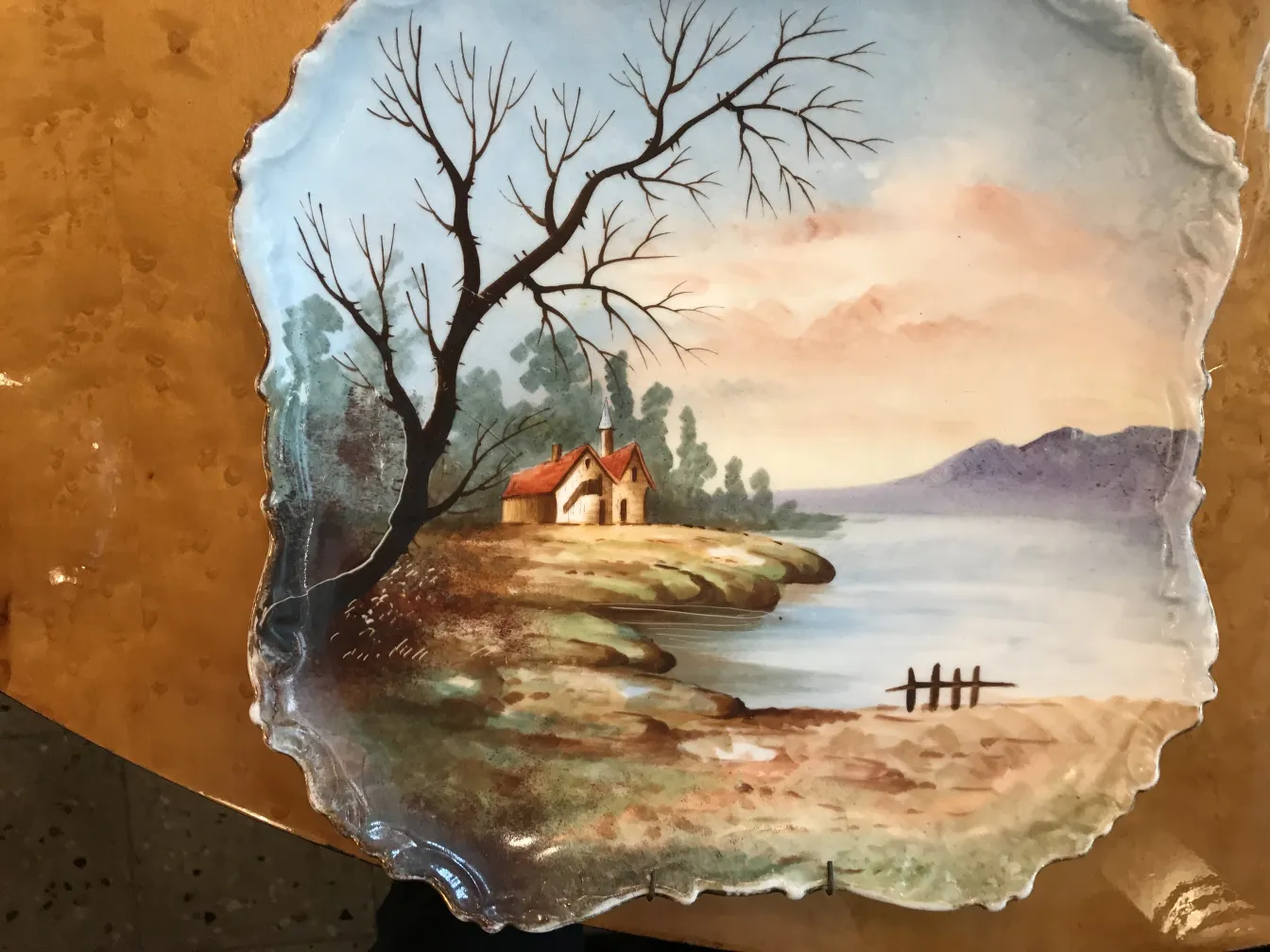 Antique ceramic plate featuring a mountain and lake landscape