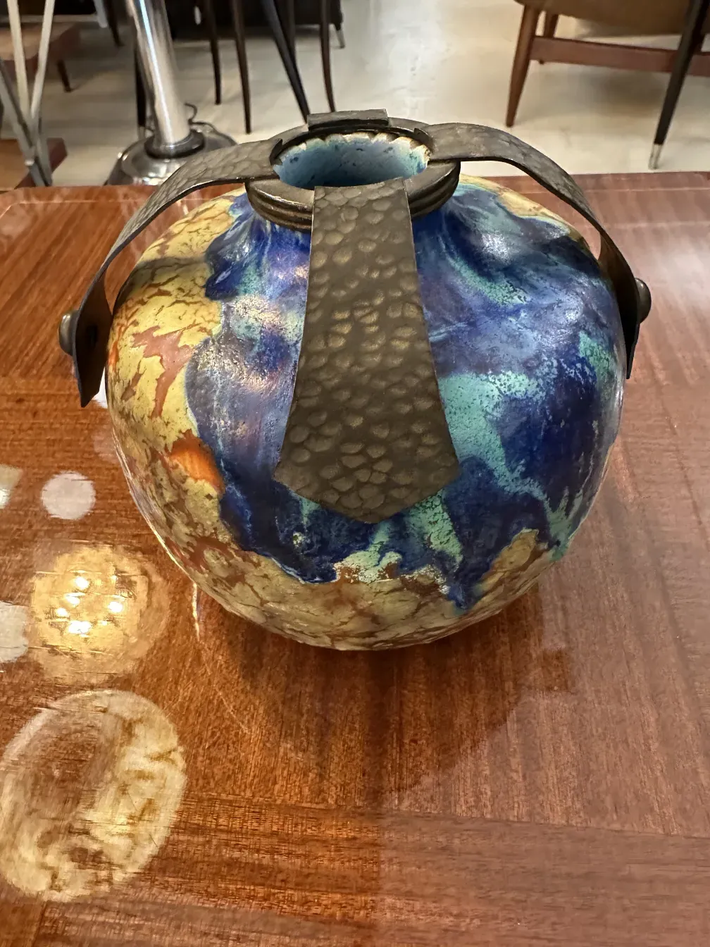 Top view of antique ceramic with vibrant colors and striking design, shiny wooden table background.