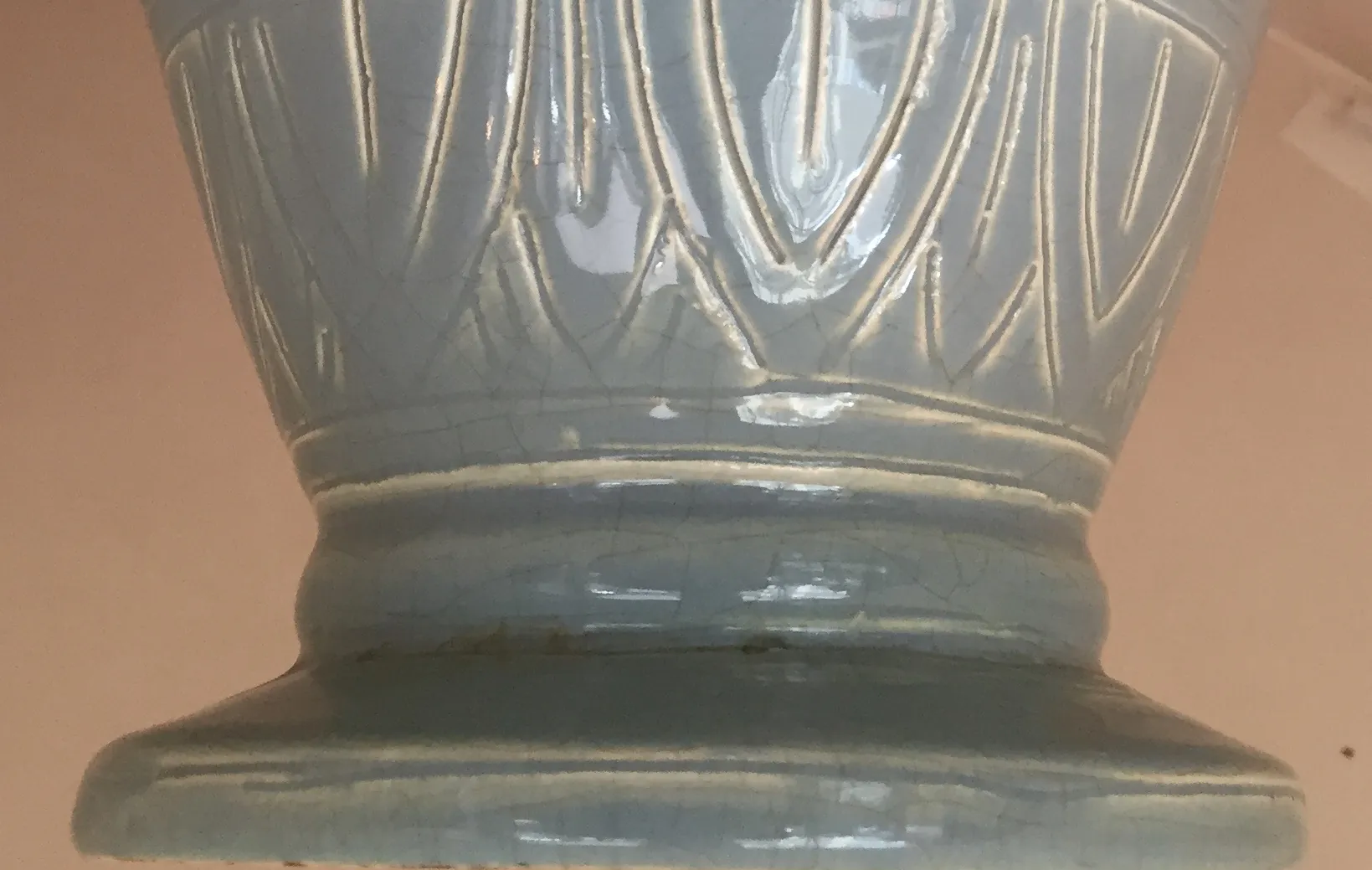 Antique ceramic vase with a subtle relief design and gloss, blurred background.