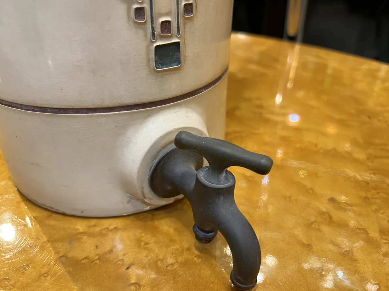 Detailed antique ceramic with black tap on shiny table.