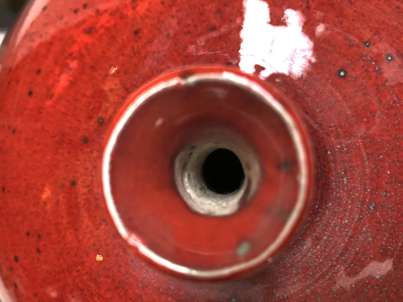 Close-up of an antique red ceramic with a hole.