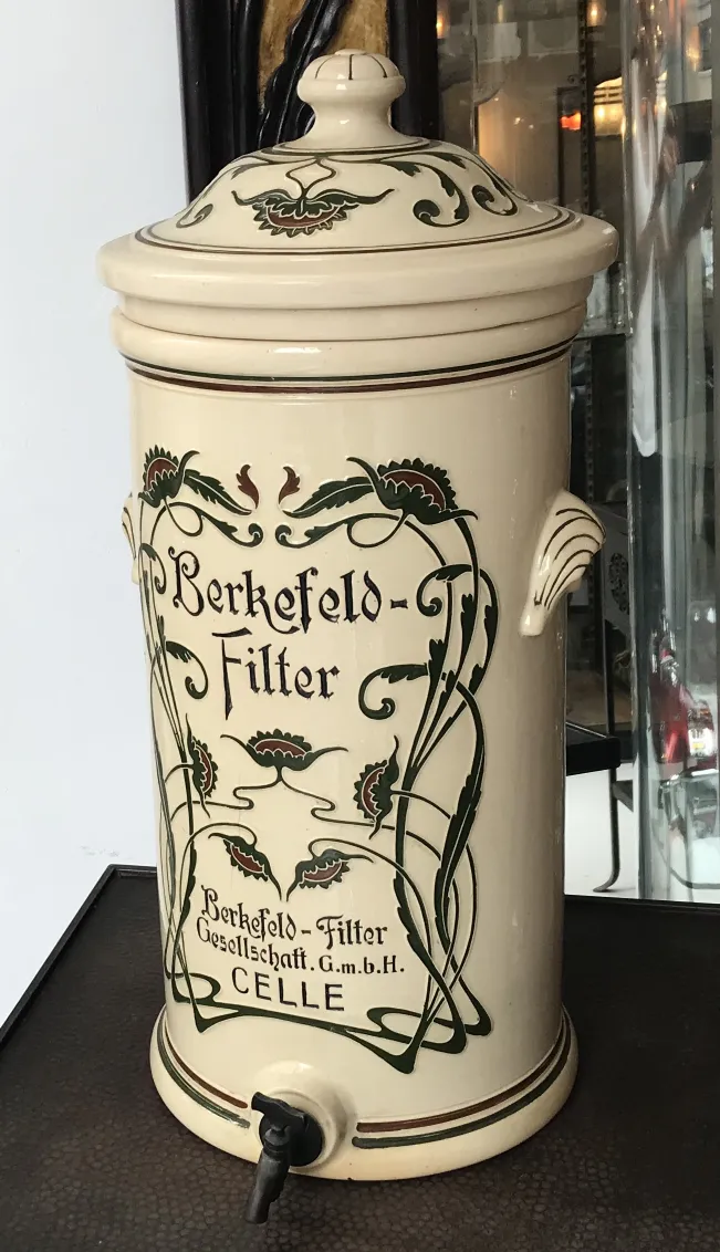 Antique ceramic pitcher with floral decoration in light tones.