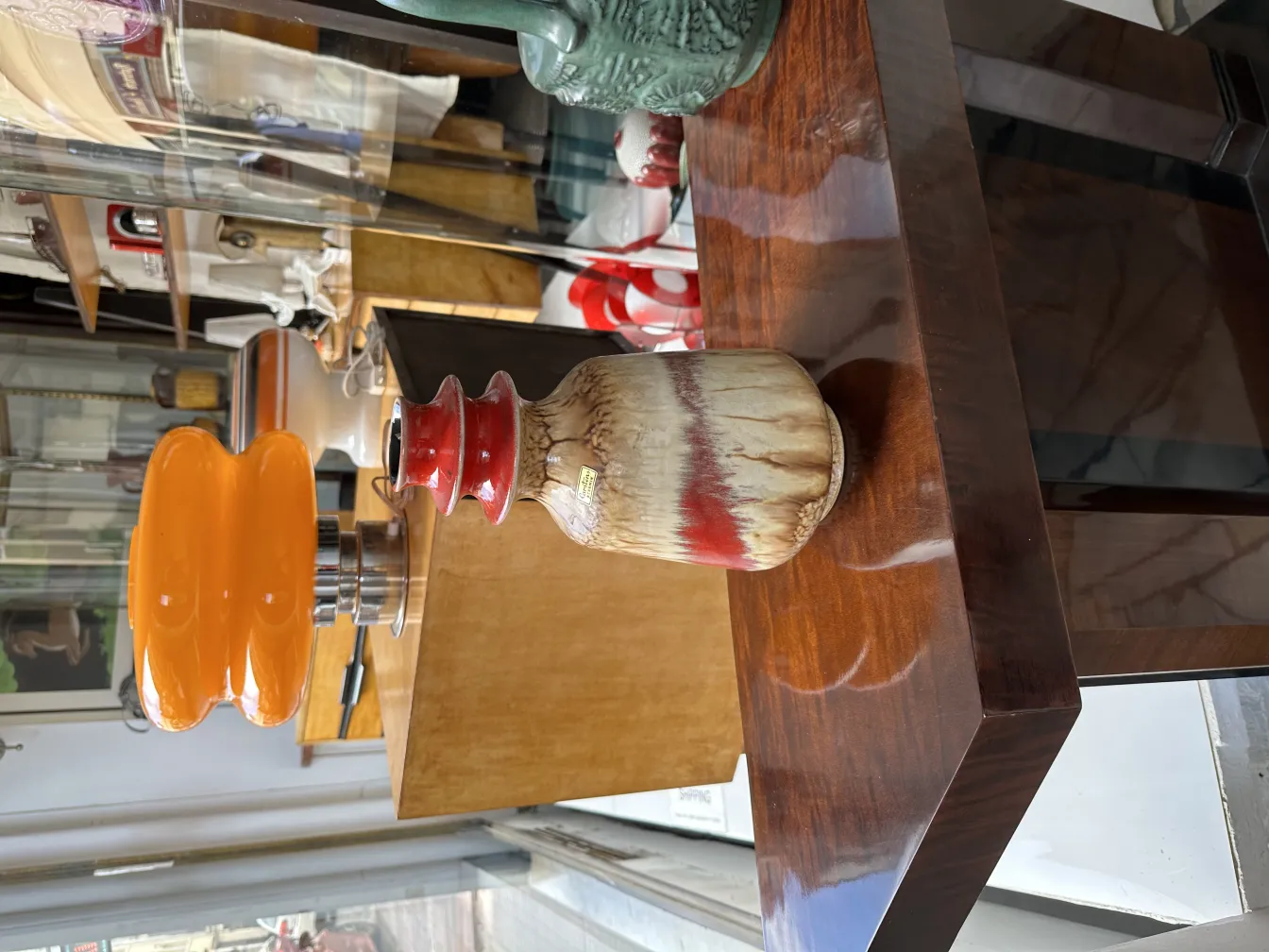 Antique ceramic vase with red and brown details, surrounded by other decorative items.