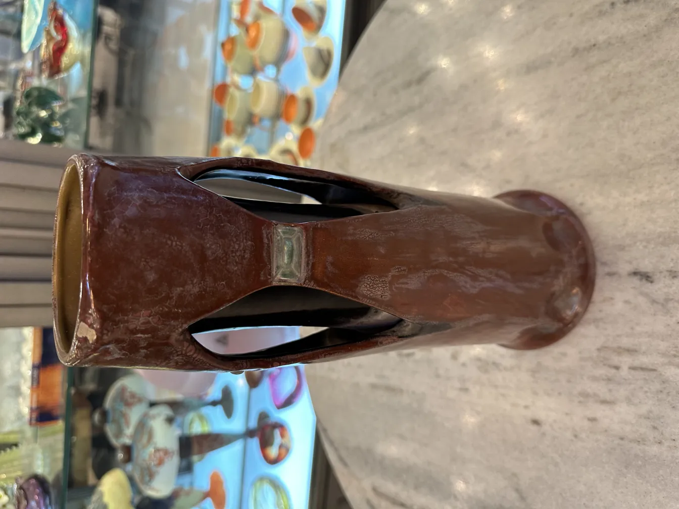 Antique brown ceramic vase with cut-out design.