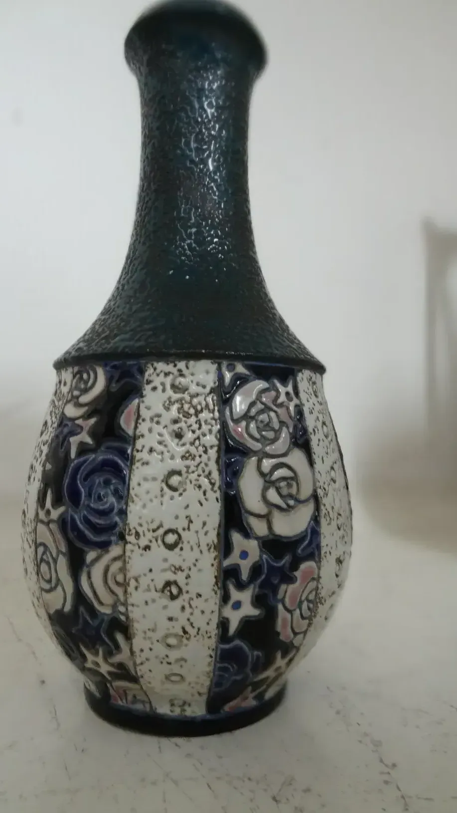 Antique ceramic vase decorated with blue and pink flowers on a white background.