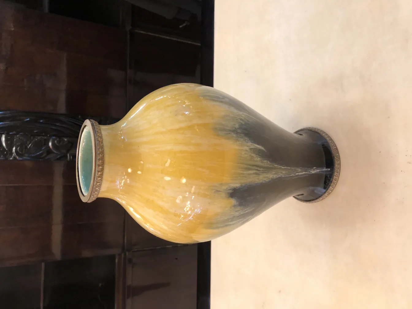 Antique ceramic vase in yellow and black design, set in a stylish environment.