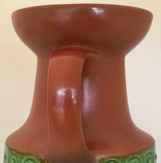 Antique ceramic pitcher with a green handle and circular patterns