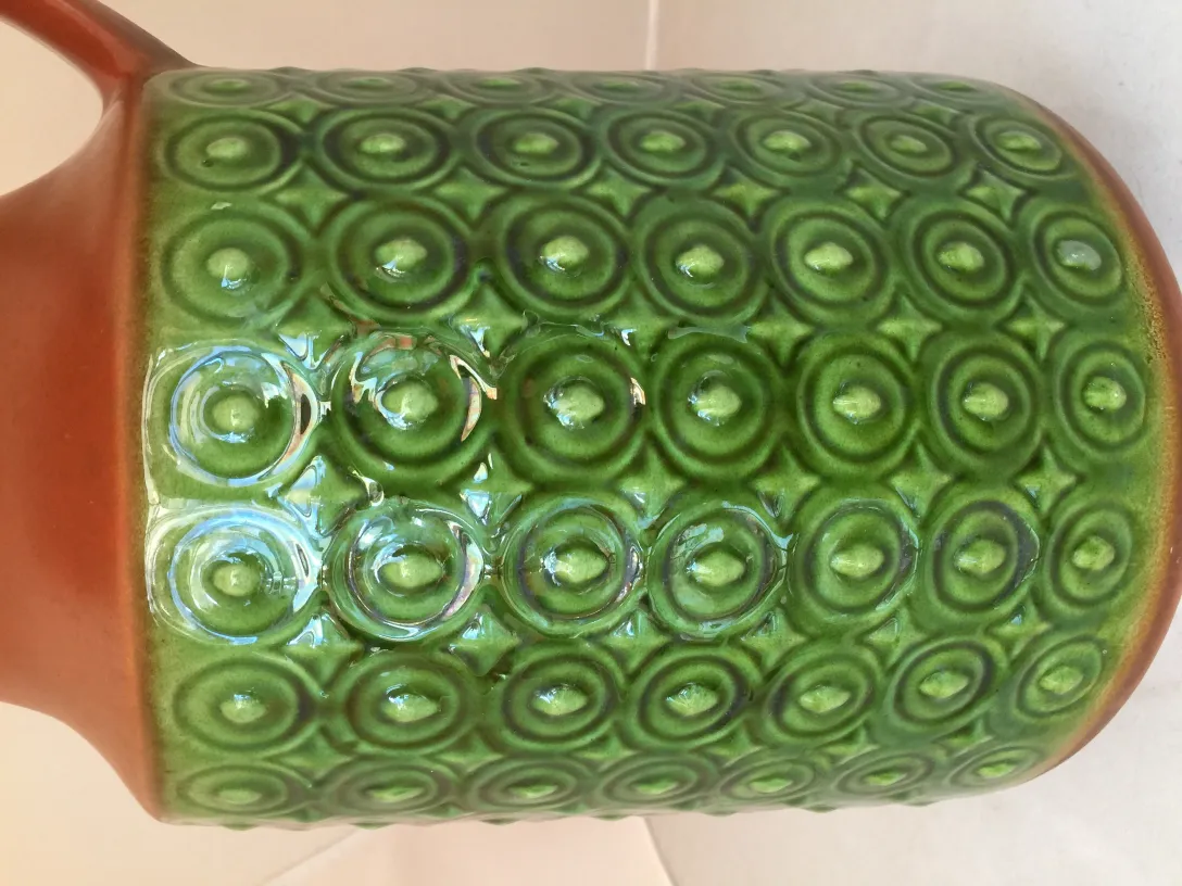 Antique green ceramic jug with circular pattern, elegantly textured design, perfect for decoration.