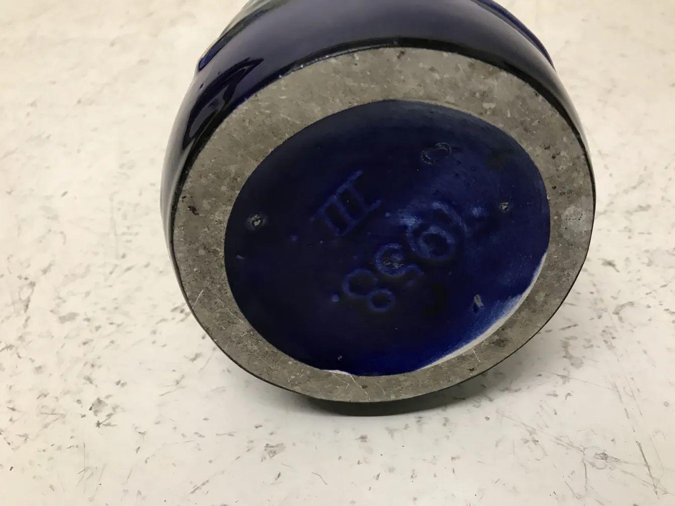 Antique blue ceramic with details on the base, light background.