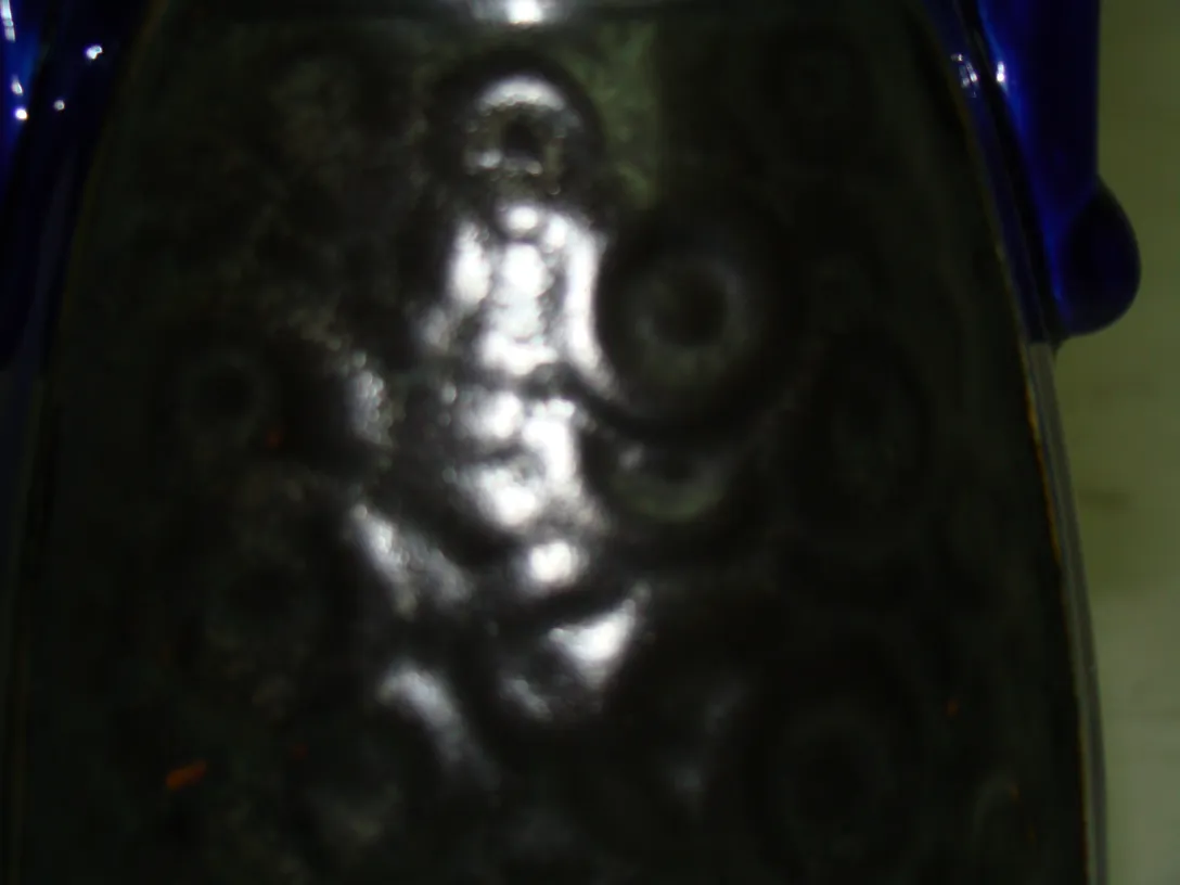 Antique decorative ceramic with embossed patterns and dark colors.