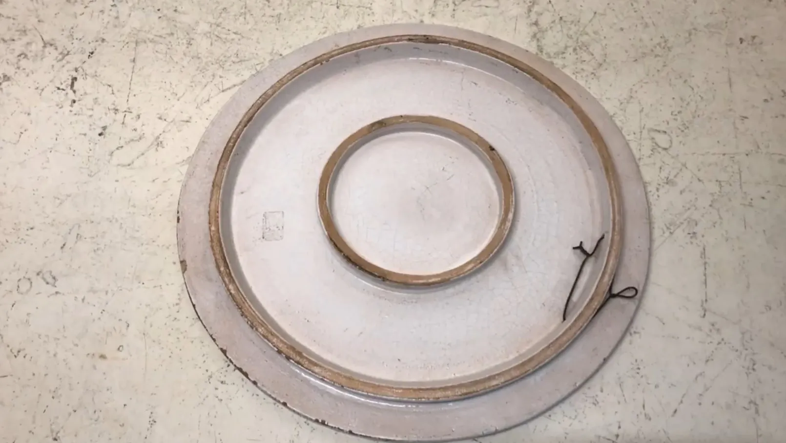 Antique ceramic plate with golden details and round shape on a light background.