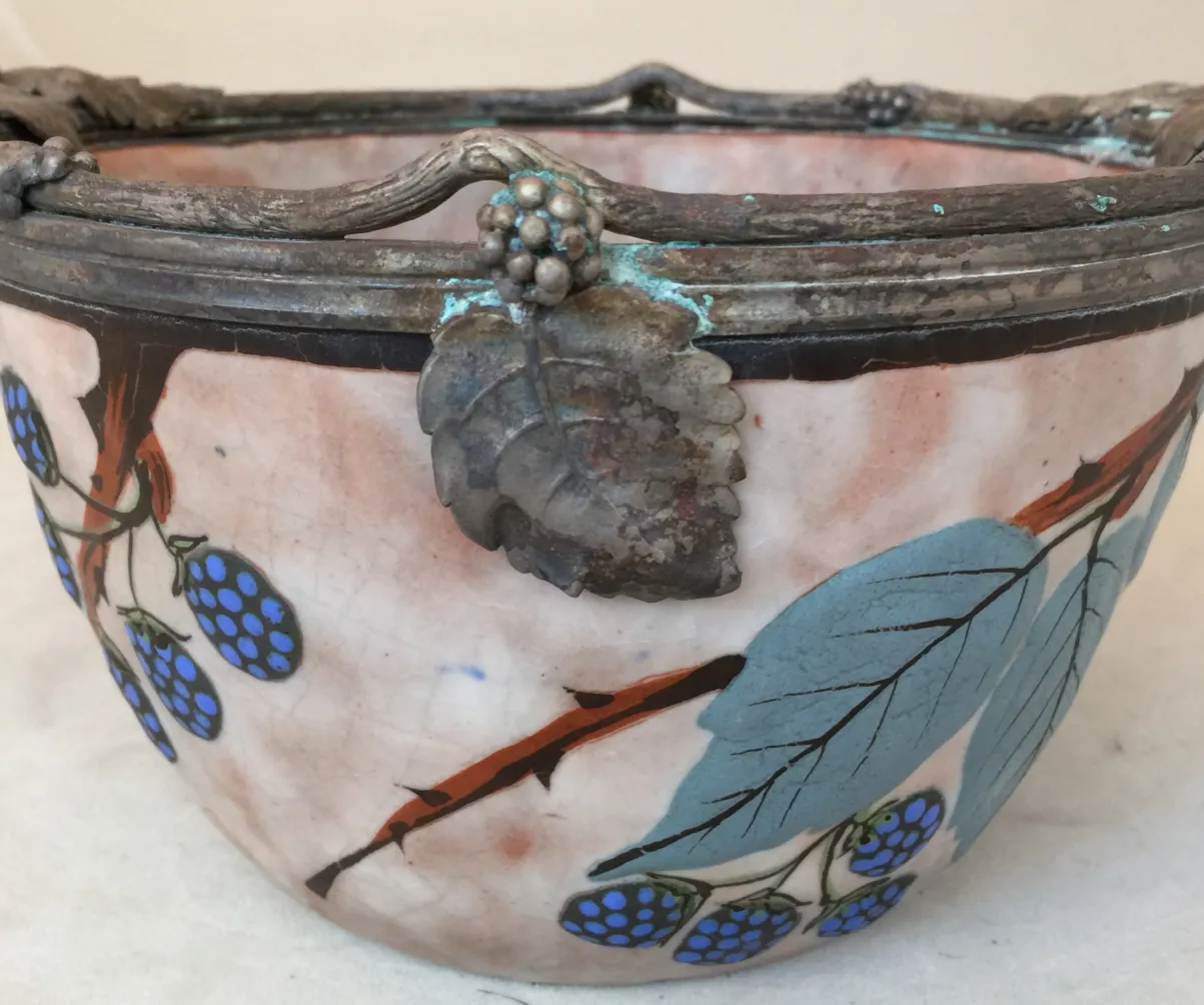 Antique ceramic bowl adorned with blue fruits and leaves.