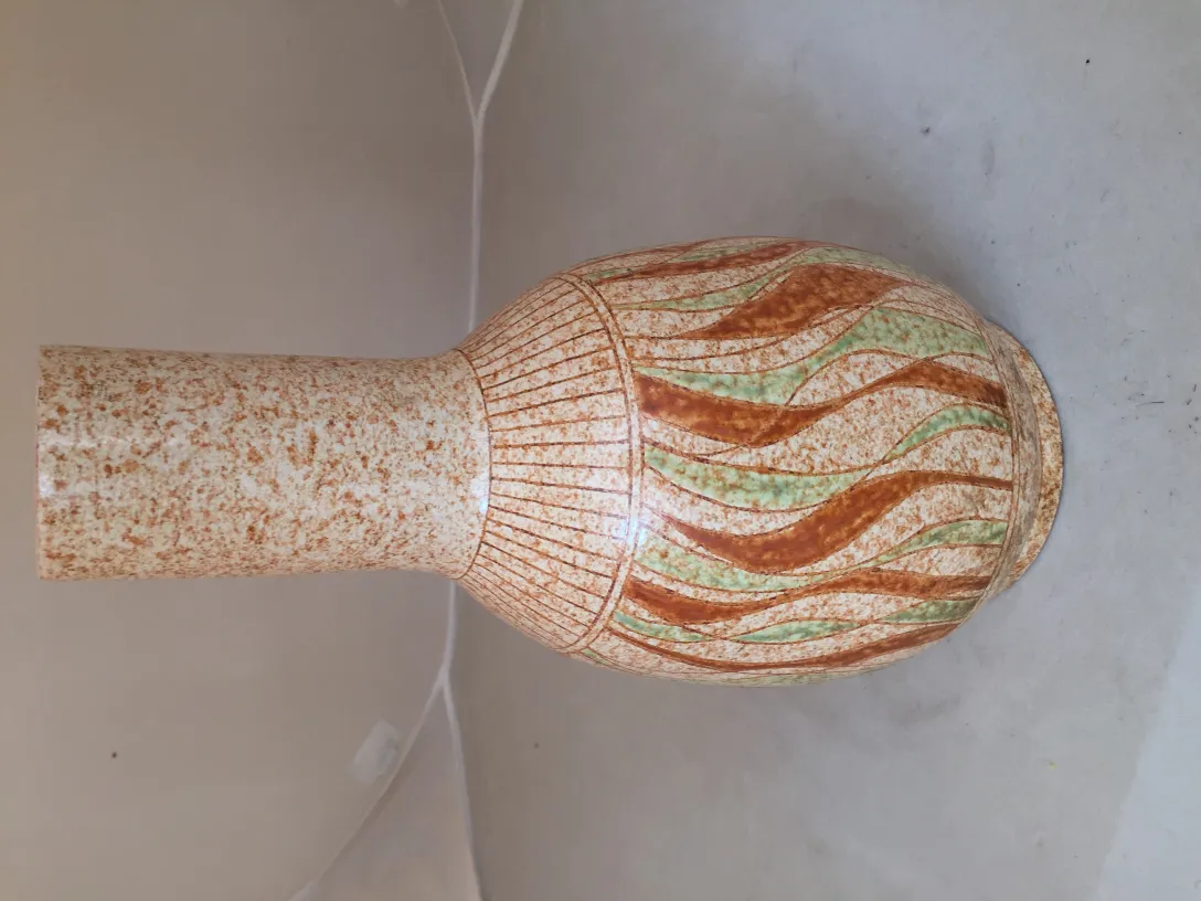 Antique ceramic vase with wavy design in brown and green tones.