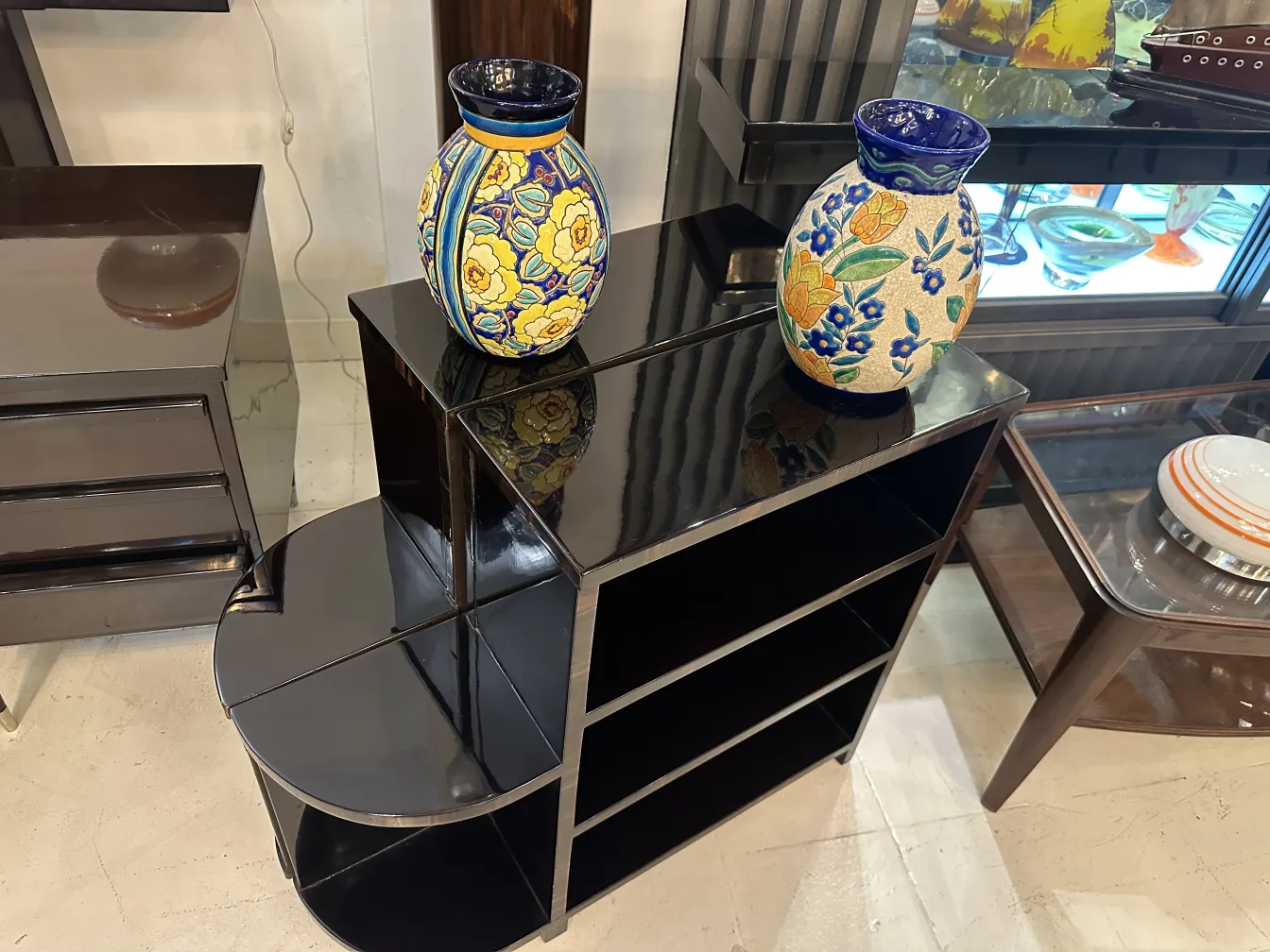 Two antique ceramic vases with flowers on a shelf.