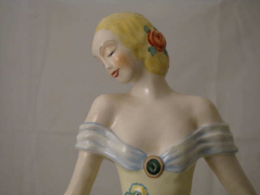 Antique decorative ceramic figure with floral details and classic dress