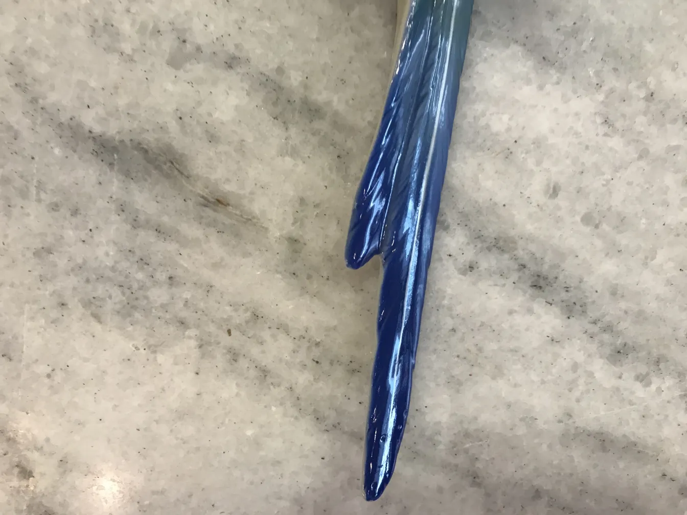 Antique ceramic piece with shiny blue glaze on light background.