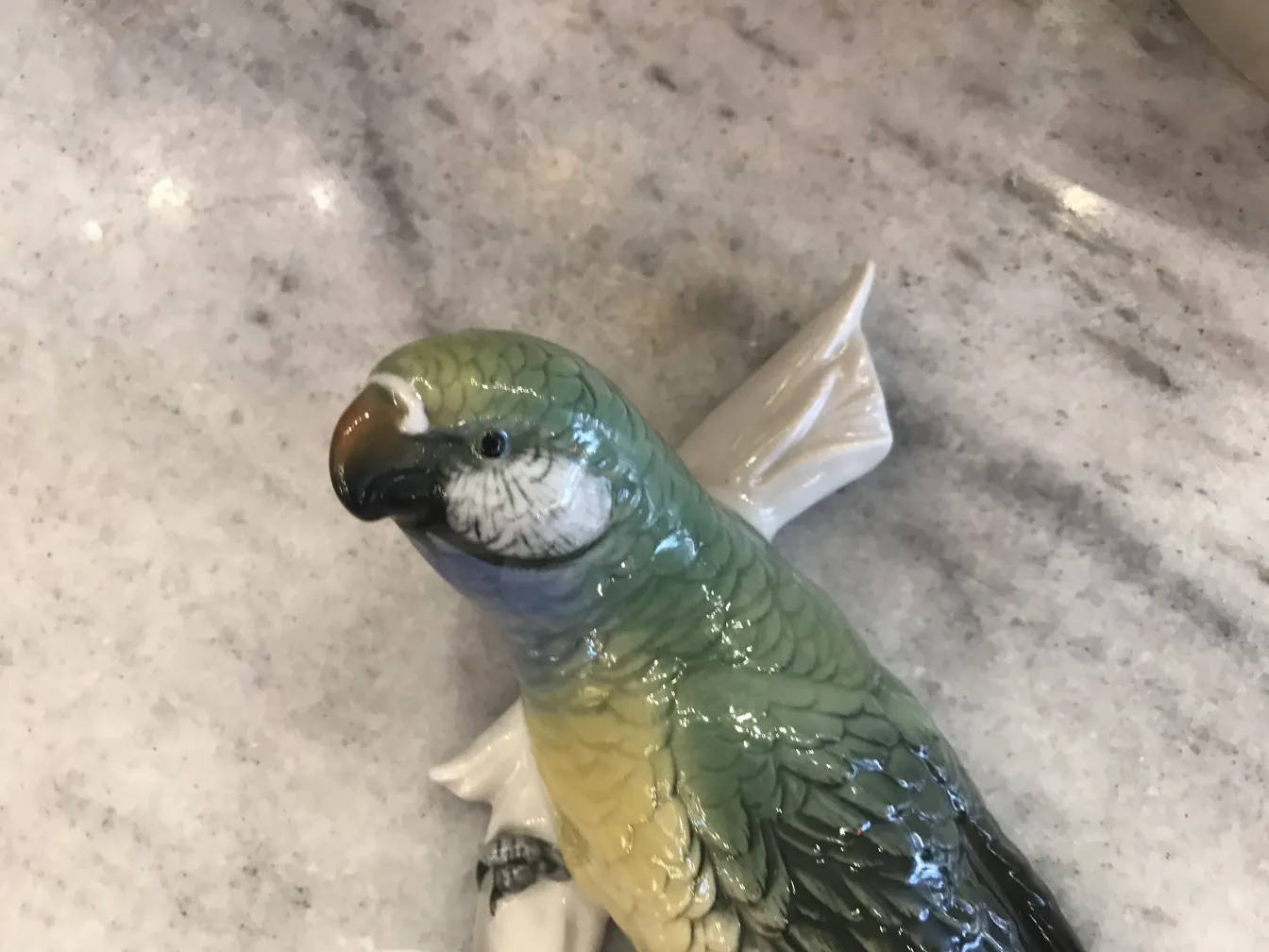 Antique ceramic figure of a colorful bird on a light surface.