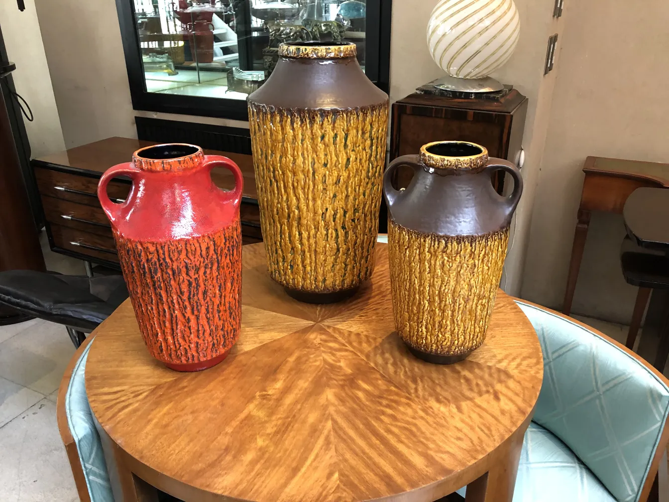 Three antique ceramic vases in bright colors on a wooden table.