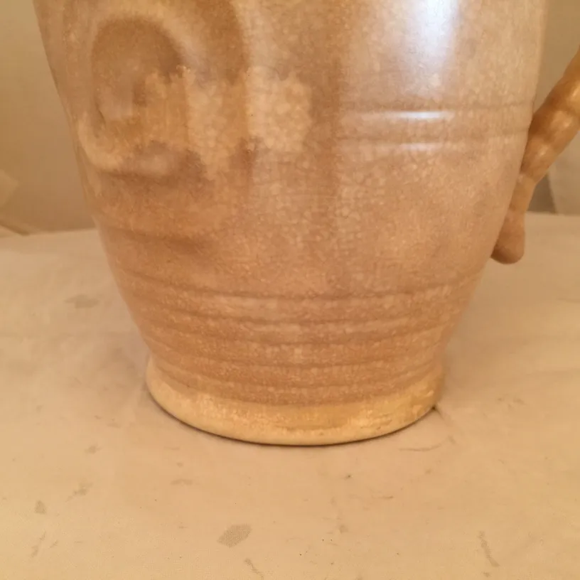 Antique ceramic jug with handcrafted texture and neutral tones.