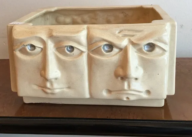 Ancient ceramic container featuring human faces