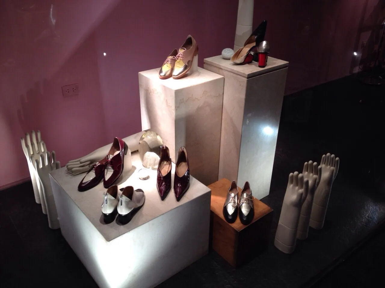 Elegant antique ceramics displayed alongside decorative shoes and hands.