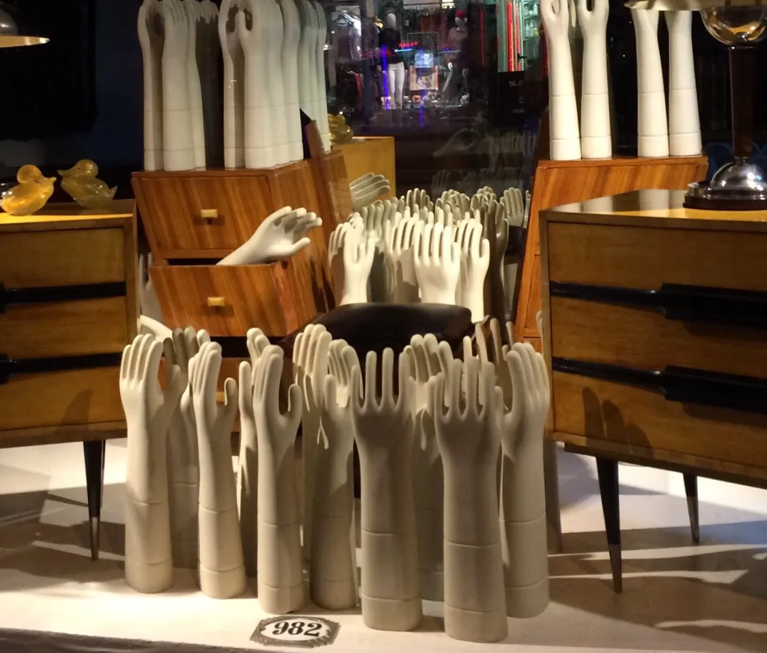 Several antique ceramic hand models shown, surrounded by wooden furniture.
