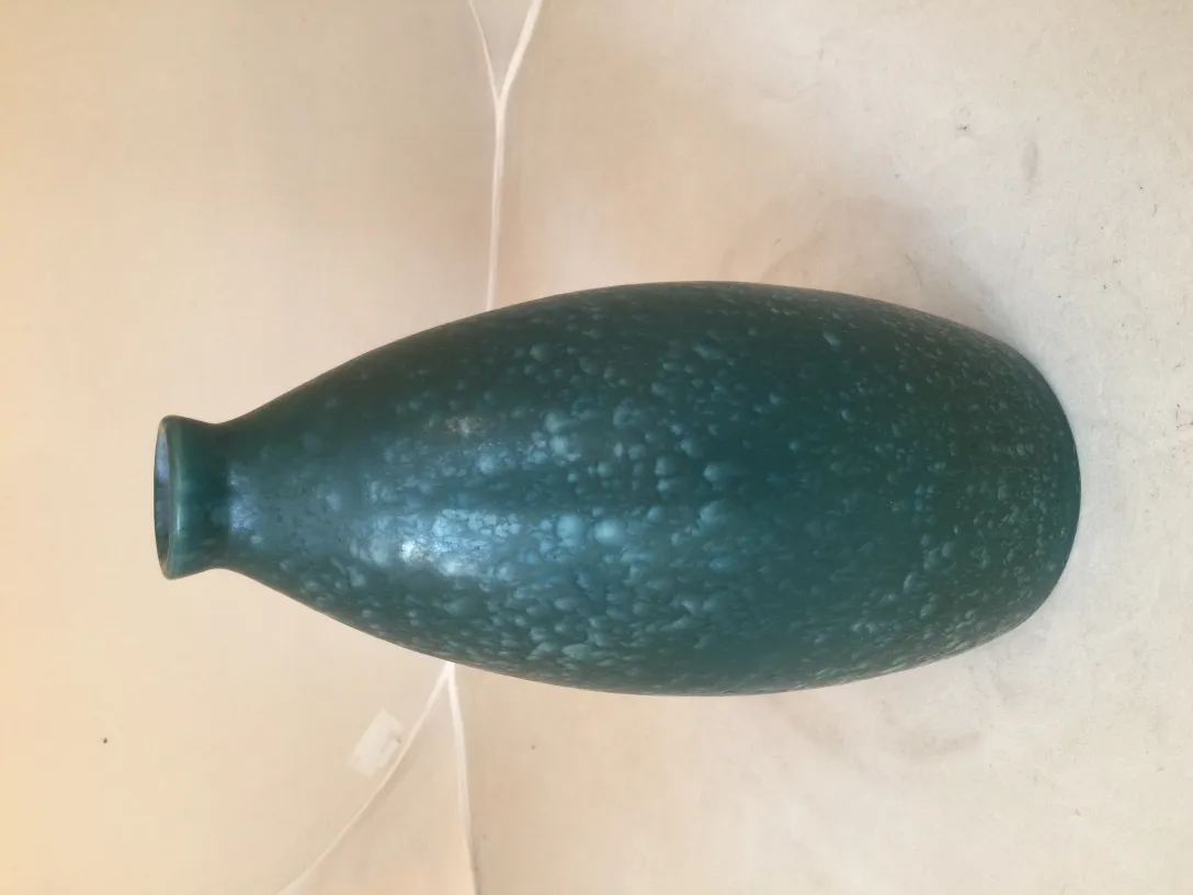 Ancient dark green ceramic vase with a textured surface.