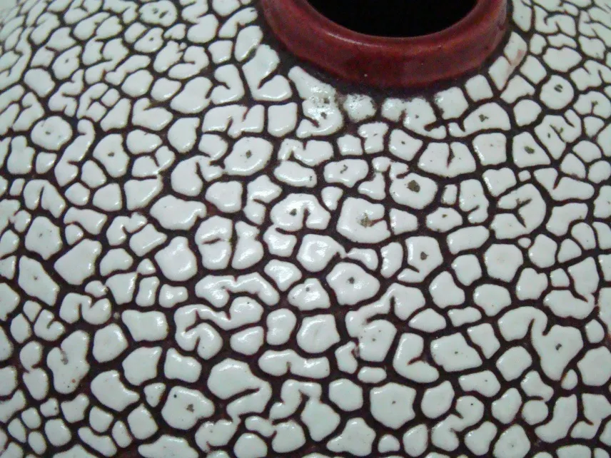 Antique ceramic with cracked texture in brown and white tones.