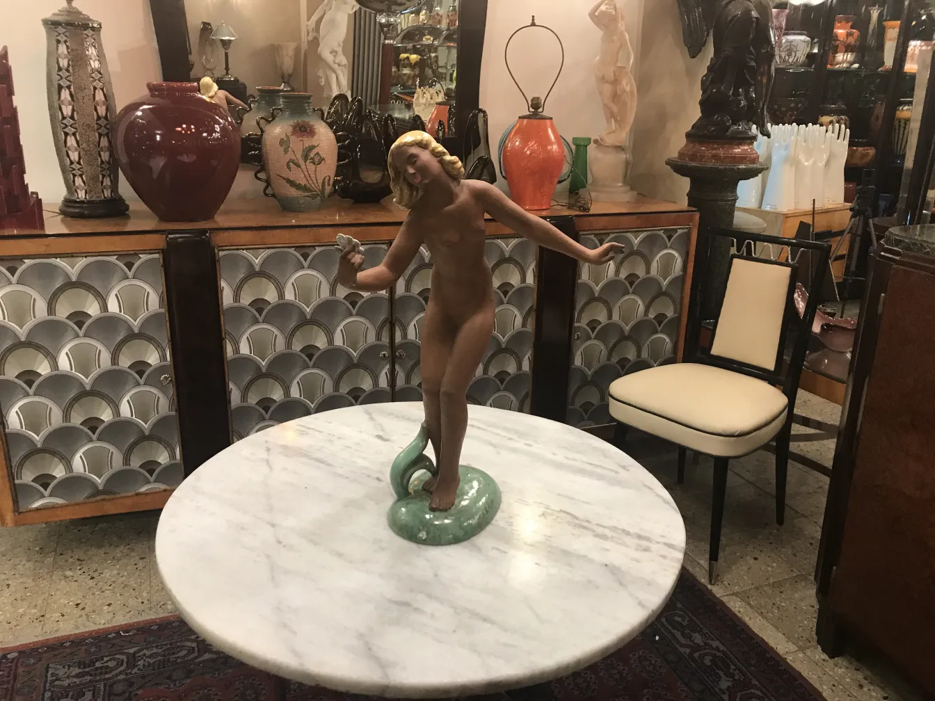 antique ceramic sculpture featuring a female figure and serpent, varied decorative background