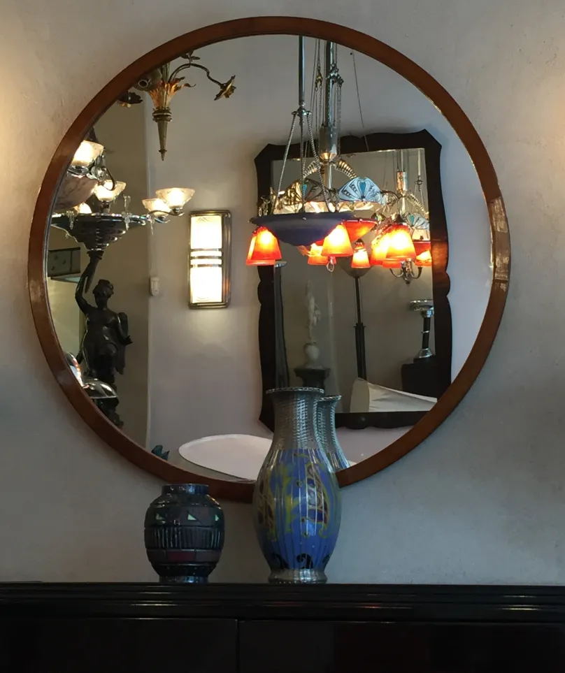 Two decorative antique ceramic vases on a table, reflected in a round mirror.