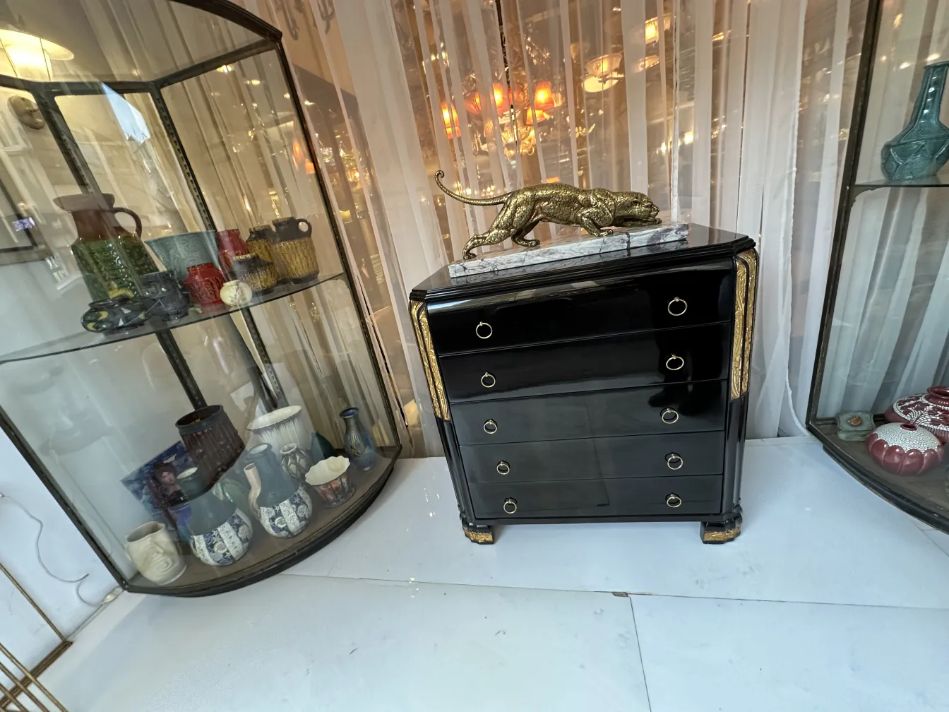 Black antique cabinet with gold details and a decorative object on top.