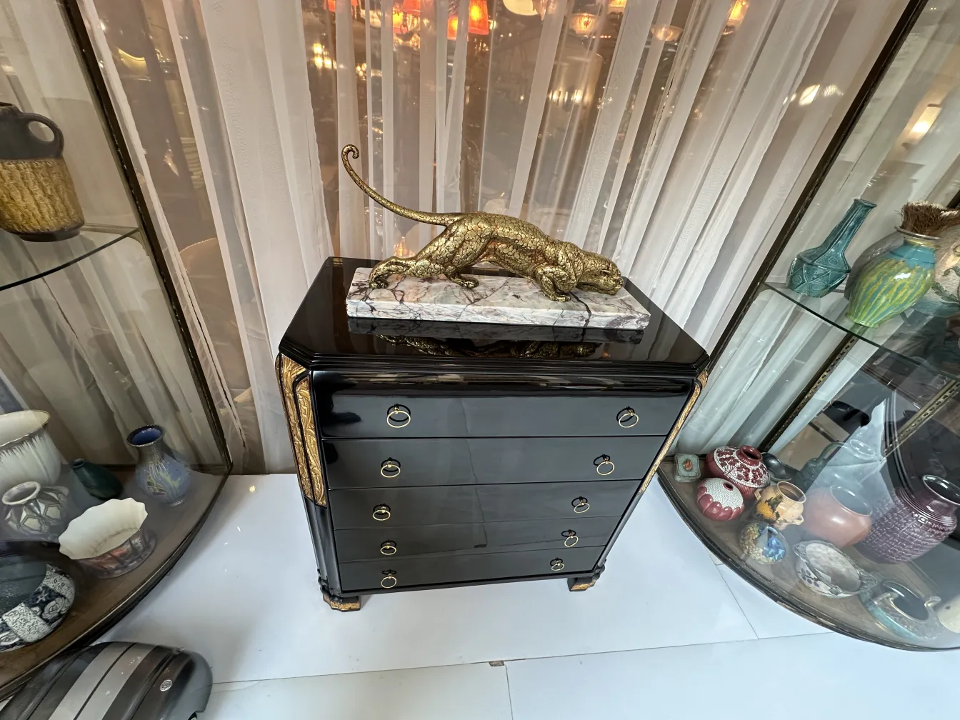 Antique black cabinet with gold accents and a statue on top