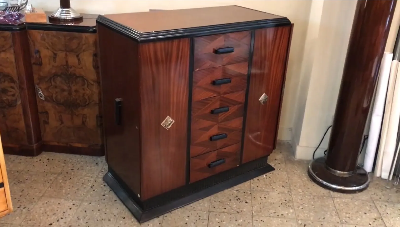 Antique cabinet with wooden finish and ten black drawers.