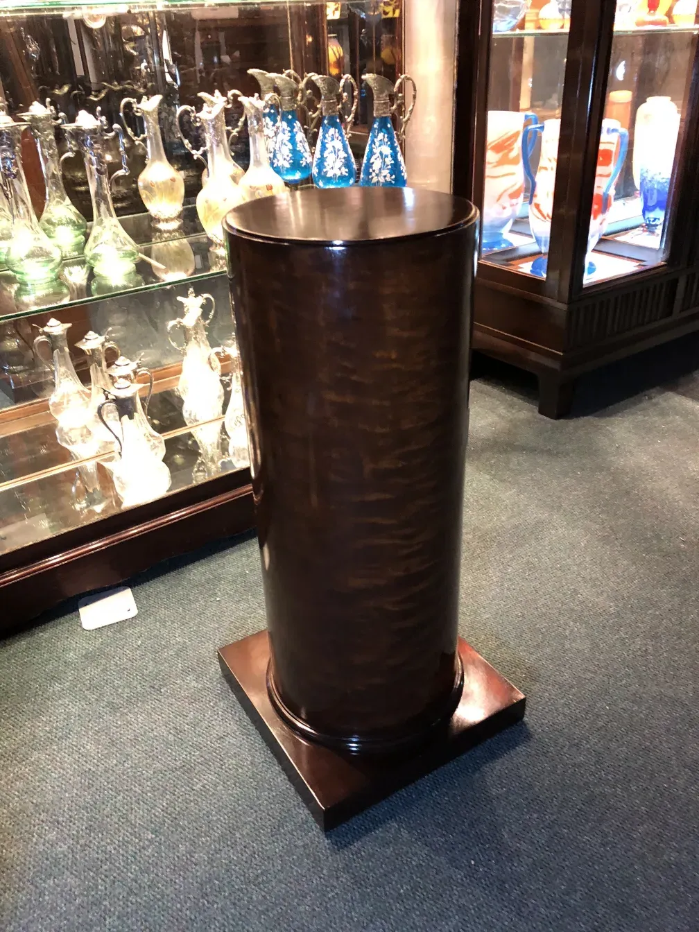 Decorative antique column with elegant design, surrounded by antiques.