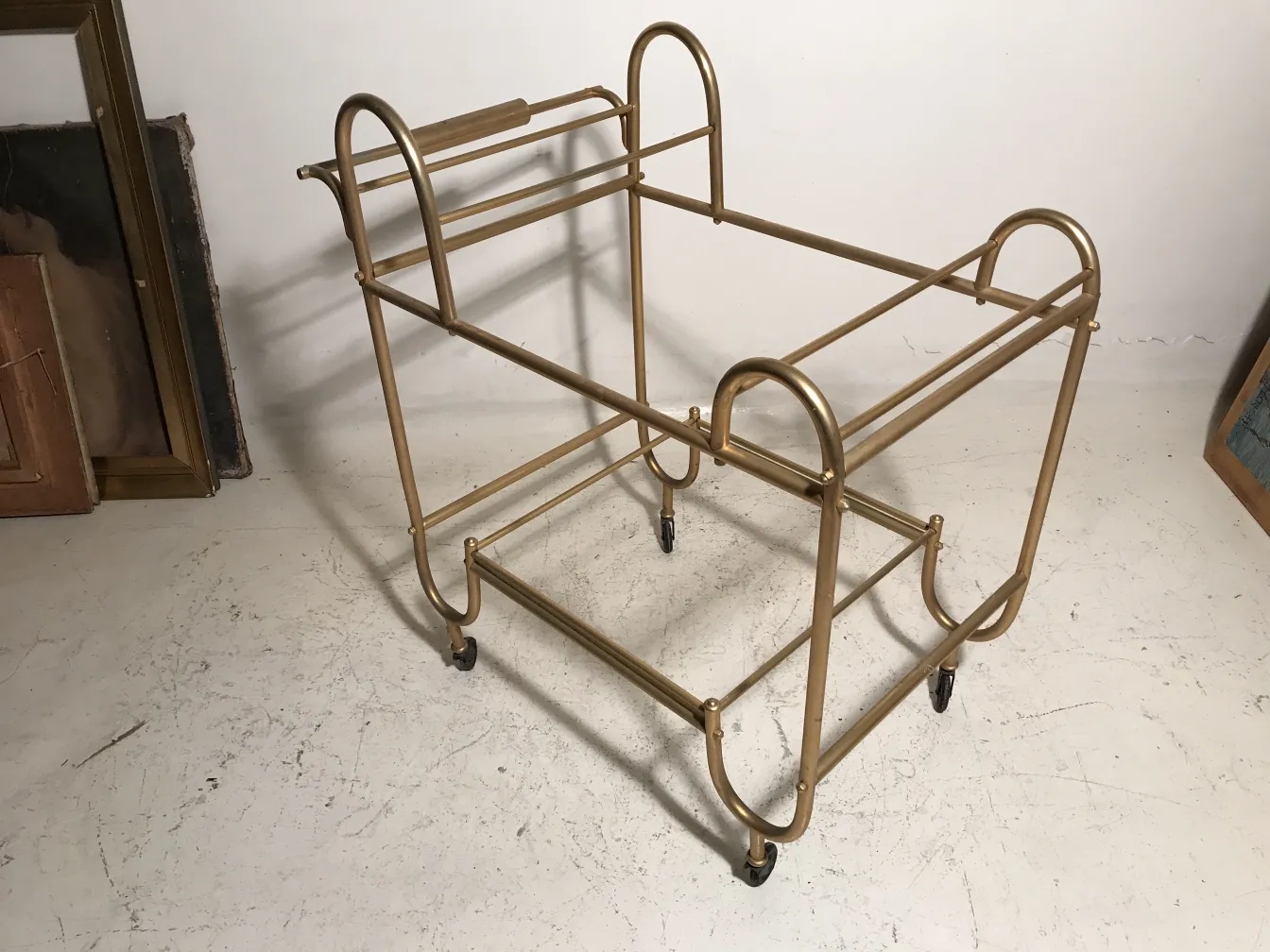 Antique cocktail trolley with a golden frame and wheels, simple setting.