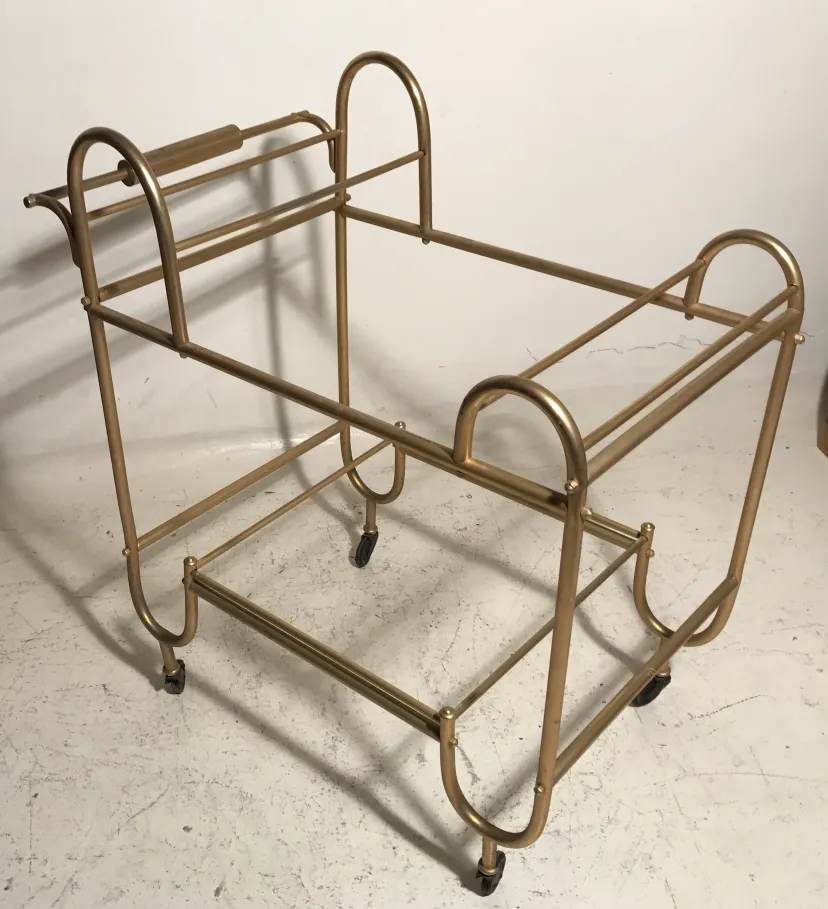 Antique cocktail trolley with gold frame and wheels.