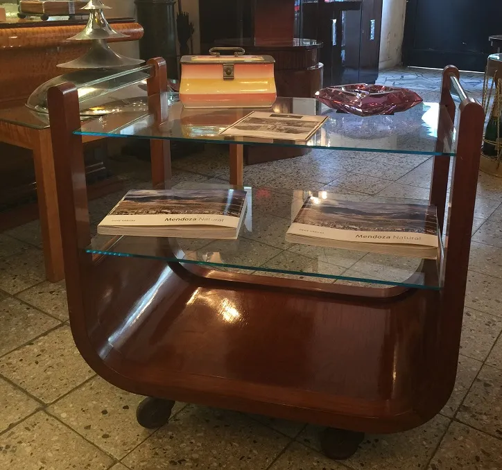 Antique cocktail trolley with glass shelves and books.